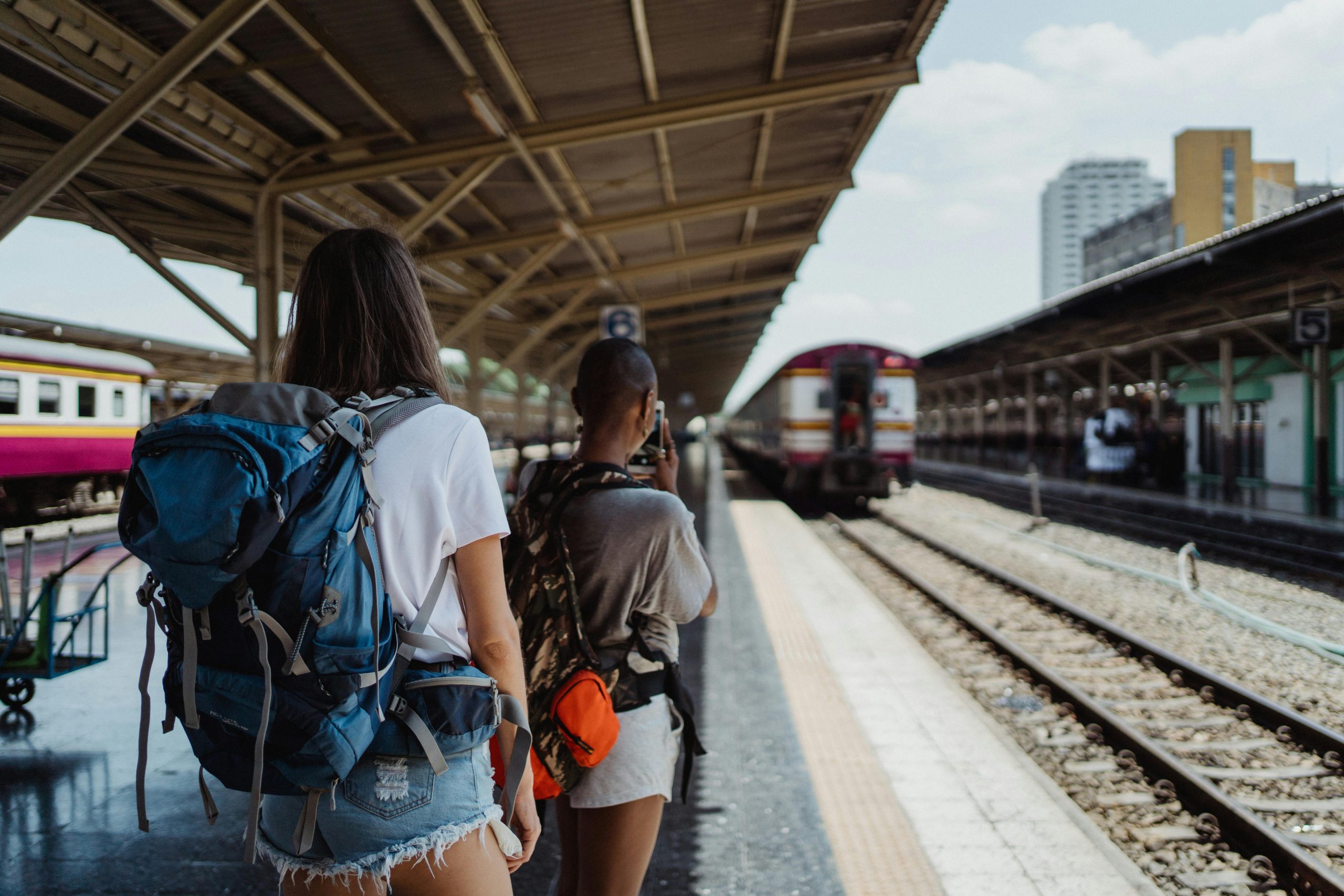Two backpackers waiting at a railway station, ready for their travel adventure.